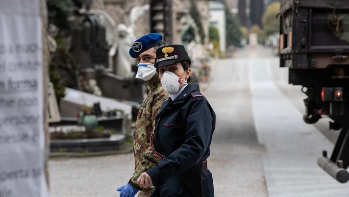 BERGAMO, ITALY - MARCH 26: An Italian Army officer and a Carabinieri officer walk past a military vehicle in the Monumental Cemetery on March 26, 2020 in Bergamo, near Milan, Italy. The Italian Army has been brought in to ferry coffins out of Bergamo, amongst Italy's most plagued towns, as its morgue and its crematorium struggle to cope with the surging coronavirus death toll. The Italian government continues to enforce the nationwide lockdown measures to control the spread of COVID-19. (Photo by Emanuele Cremaschi/Getty Images) BERGAMO, ITALY - MARCH 26: An Italian Army officer and a Carabinieri officer walk past a military vehicle in the Monumental Cemetery on March 26, 2020 in Bergamo, near Milan, Italy. The Italian Army has been brought in to ferry coffins out of Bergamo, amongst Italy's most plagued towns, as its morgue and its crematorium struggle to cope with the surging coronavirus death toll. The Italian government continues to enforce the nationwide lockdown measures to control the spread of COVID-19. (Photo by Emanuele Cremaschi/Getty Images)