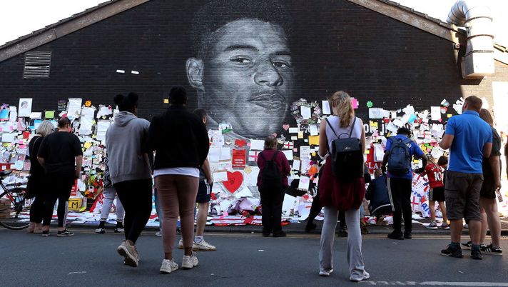 MANCHESTER, ENGLAND - JULY 14: People look at the newly repaired mural of England footballer Marcus Rashford by the artist known as AKSE_P19, which is displayed on the wall of a cafe on Copson Street, Withington on July 14, 2021 in Manchester, England. Rashford and other Black players on England's national football team have been the target of racist abuse, largely on social media, after the team's loss to Italy in the UEFA European Football Championship last night. England manager Gareth Southgate, Prime Minister Boris Johnson, and the Football Association have issued statements condemning the abuse. (Photo by Charlotte Tattersall/Getty Images) MANCHESTER, ENGLAND - JULY 14: People look at the newly repaired mural of England footballer Marcus Rashford by the artist known as AKSE_P19, which is displayed on the wall of a cafe on Copson Street, Withington on July 14, 2021 in Manchester, England. Rashford and other Black players on England's national football team have been the target of racist abuse, largely on social media, after the team's loss to Italy in the UEFA European Football Championship last night. England manager Gareth Southgate, Prime Minister Boris Johnson, and the Football Association have issued statements condemning the abuse. (Photo by Charlotte Tattersall/Getty Images)