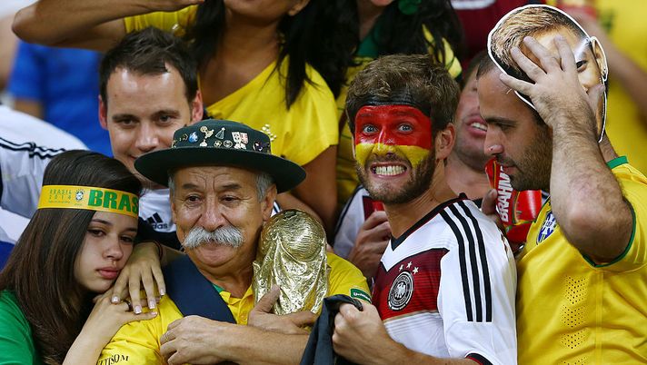 BELO HORIZONTE, BRAZIL - JULY 08: A Germany fan reacts while surrounded by dejected Brazil fans after Germany's 7-1 win during the 2014 FIFA World Cup Brazil Semi Final match between Brazil and Germany at Estadio Mineirao on July 8, 2014 in Belo Horizonte, Brazil. (Photo by Michael Steele/Getty Images) Sulle auto o sugli alberi, viaggi infiniti, false identità, atti osceni: le follie dei tifosi…- immagine 2