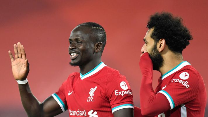 LIVERPOOL, ENGLAND - DECEMBER 06: Sadio Mane of Liverpool celebrates with team mate Mohamed Salah after an own goal from Nelson Semedo (Not pictured) of Wolverhampton Wanderers during the Premier League match between Liverpool and Wolverhampton Wanderers at Anfield on December 06, 2020 in Liverpool, England. A limited number of fans (2000) are welcomed back to stadiums to watch elite football across England. This was following easing of restrictions on spectators in tiers one and two areas only. (Photo by Peter Powell - Pool/Getty Images) La finale di coppa d’Africa è il derby dei Reds: Momo Salah contro Sadio Mané - immagine 1