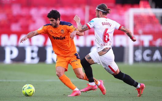SEVILLE, SPAIN - MAY 12: Goncalo Guedes of Valencia CF runs with the ball whilst under pressure from Nemanja Gudelj of Sevilla during the La Liga Santander match between Sevilla FC and Valencia CF at Estadio Ramon Sanchez Pizjuan on May 12, 2021 in Seville, Spain. Sporting stadiums around Spain remain under strict restrictions due to the Coronavirus Pandemic as Government social distancing laws prohibit fans inside venues resulting in games being played behind closed doors. (Photo by Fran Santiago/Getty Images) SEVILLE, SPAIN - MAY 12: Goncalo Guedes of Valencia CF runs with the ball whilst under pressure from Nemanja Gudelj of Sevilla during the La Liga Santander match between Sevilla FC and Valencia CF at Estadio Ramon Sanchez Pizjuan on May 12, 2021 in Seville, Spain. Sporting stadiums around Spain remain under strict restrictions due to the Coronavirus Pandemic as Government social distancing laws prohibit fans inside venues resulting in games being played behind closed doors. (Photo by Fran Santiago/Getty Images)