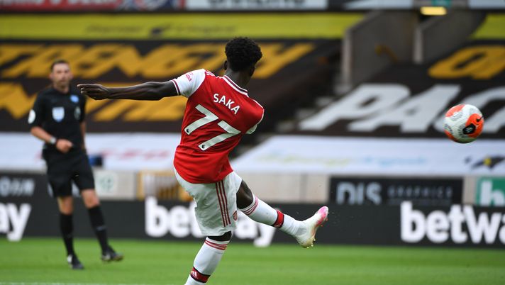 WOLVERHAMPTON, ENGLAND - JULY 04: Bukayo Saka of Arsenal scores a goal to make it 0-1 during the Premier League match between Wolverhampton Wanderers and Arsenal FC at Molineux on July 4, 2020 in Wolverhampton, United Kingdom. Football Stadiums around Europe remain empty due to the Coronavirus Pandemic as Government social distancing laws prohibit fans inside venues resulting in all fixtures being played behind closed doors. (Photo by Sam Bagnall - AMA/Getty Images) WOLVERHAMPTON, ENGLAND - JULY 04: Bukayo Saka of Arsenal scores a goal to make it 0-1 during the Premier League match between Wolverhampton Wanderers and Arsenal FC at Molineux on July 4, 2020 in Wolverhampton, United Kingdom. Football Stadiums around Europe remain empty due to the Coronavirus Pandemic as Government social distancing laws prohibit fans inside venues resulting in all fixtures being played behind closed doors. (Photo by Sam Bagnall - AMA/Getty Images)
