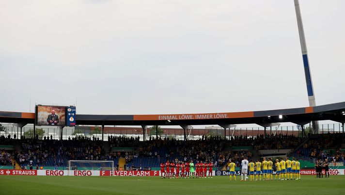 BRAUNSCHWEIG, GERMANY - JULY 31: The teams line up for a moment of silence ahead of the DFB Cup first round match between Eintracht Braunschweig and Hertha BSC at Eintracht Stadion on July 31, 2022 in Braunschweig, Germany. (Photo by Martin Rose/Getty Images) Rigori fatali, Hertha ko in coppa: ma gli ultras caricano la squadra per il derby di Berlino - immagine 1