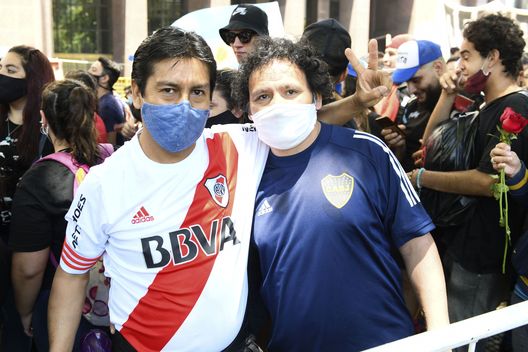BUENOS AIRES, ARGENTINA - NOVEMBER 26: A River Plate and Boca Juniors fan pose for a picture together as they queue in line to pay tribute to Diego Maradona in the goverment palace on November 26, 2020 in Buenos Aires, Argentina. Maradona died of a heart attack at his home on Thursday 25 aged 60 . He is considered among the best footballers in history and lead his national team to the World Cup in 1986. President of Argentina Alberto Fernandez declared three days of national mourning. (Photo by Rodrigo Valle/Getty Images) Compleanno di Maradona, è la “Giornata del calcio”: regalare un pallone a un bambino- immagine 2