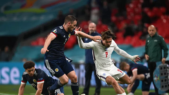 LONDON, ENGLAND - JUNE 18: Jack Grealish of England runs with the ball whilst under pressure from Stephen O'Donnell and Che Adams of Scotland during the UEFA Euro 2020 Championship Group D match between England and Scotland at Wembley Stadium on June 18, 2021 in London, England. (Photo by Andy Rain - Pool/Getty Images)