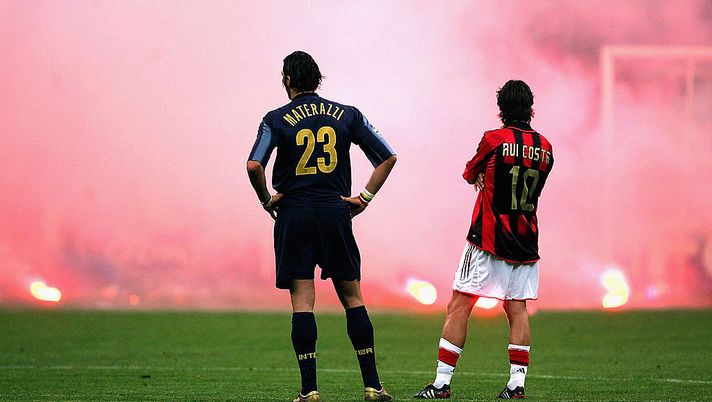 MILAN, ITALY - APRIL 12: Marco Materazzi of Inter Milan and Rui Costa of AC Milan look on as Inter fans shower the pitch with flares during the UEFA Champions League quarter-final second leg between AC Milan and Inter Milan at the San Siro Stadium on April 12, 2005 in Milan, Italy. (Photo by Mike Hewitt/Getty Images) Chiodo fisso derby, Marco Materazzi: “Fino al 75′ l’Inter aveva lo scudetto in mano…” - immagine 1