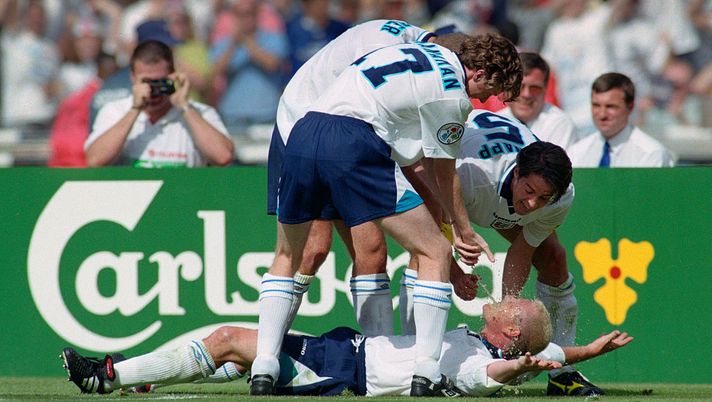 LONDON, UNITED KINGDOM - JUNE 15: England goalscorer Paul Gascoigne celebrates in the 'Dentists Chair' with Steve McManaman (l) Alan Shearer (obscured) and Jamie Redknapp during the 1996 European Championships group stage match against Scotland at Wembley Stadium on June 15, 1996 in London, England. (Photo by Stu Forster/Allsport/Getty Images) Qatar 2022, primo Mondiale senza Maradona: quando Gascoigne gli disse “sono brillo” e Diego rispose “Anche io” - immagine 1