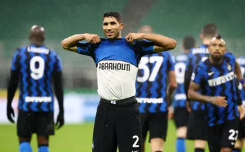  MILAN, ITALY - DECEMBER 05: Achraf Hakimi of Inter Milan celebrates after scoring their team's second goal whilst showing a t-shirt in memory of ex-Moroccan player Mohamed Aberhoun during the Serie A match between FC Internazionale and Bologna FC at Stadio Giuseppe Meazza on December 05, 2020 in Milan, Italy. Football Stadiums around Italy remain empty due to the Coronavirus Pandemic as Government social distancing laws prohibit fans inside venues resulting in fixtures being played behind closed doors. (Photo by Marco Luzzani/Getty Images)