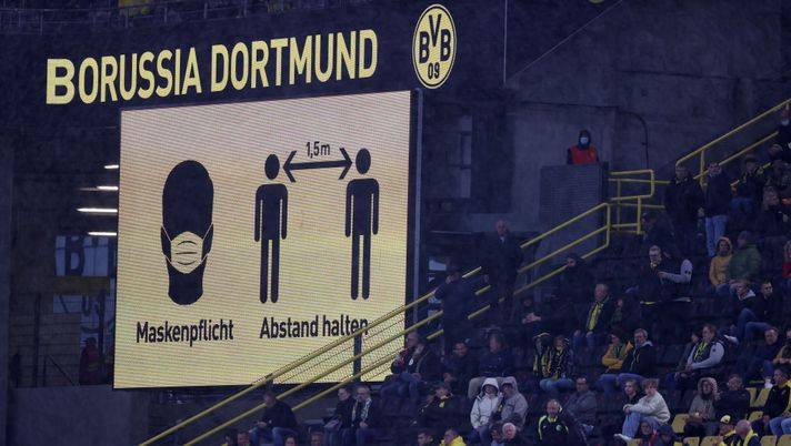 DORTMUND, GERMANY - OCTOBER 03: Fans look on from the stands as a screen in the stadium asks fans to wear face masks and to respect social distancing guidlines during the Bundesliga match between Borussia Dortmund and Sport-Club Freiburg at Signal Iduna Park on October 03, 2020 in Dortmund, Germany. A limited number of fans have been allowed into the stadium as COVID-19 precautions ease in Germany. (Photo by Lars Baron/Getty Images) DORTMUND, GERMANY - OCTOBER 03: Fans look on from the stands as a screen in the stadium asks fans to wear face masks and to respect social distancing guidlines during the Bundesliga match between Borussia Dortmund and Sport-Club Freiburg at Signal Iduna Park on October 03, 2020 in Dortmund, Germany. A limited number of fans have been allowed into the stadium as COVID-19 precautions ease in Germany. (Photo by Lars Baron/Getty Images)