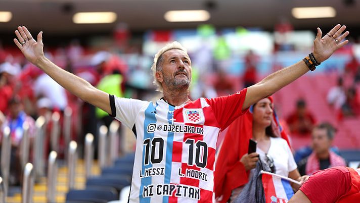 AL KHOR, QATAR - NOVEMBER 23: A fan wearing a half and half shirt with the names of Lionel Messi of Argentina and Luka Modric of Croatia on reacts prior to the FIFA World Cup Qatar 2022 Group F match between Morocco and Croatia at Al Bayt Stadium on November 23, 2022 in Al Khor, Qatar. (Photo by Lars Baron/Getty Images) TACKLE DURO – Il derby dei media su Messi contro Modric e tanto poi vince Mbappé - immagine 1
