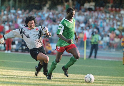 NAPLES, ITALY - JUNE 23: Cameroon striker Roger Milla walks the ball into the empty net to score the winning goal after dispossesing Colombian goalkeeper Rene Higuita (l) of the ball mid pitch during the Second phase match between Cameroon and Colombia on June 23, in Naples, Italy. (Photo by Allsport/Getty Images) Coppa d’Africa, il Burkina Faso parla di scandalo per i controlli Covid- immagine 2