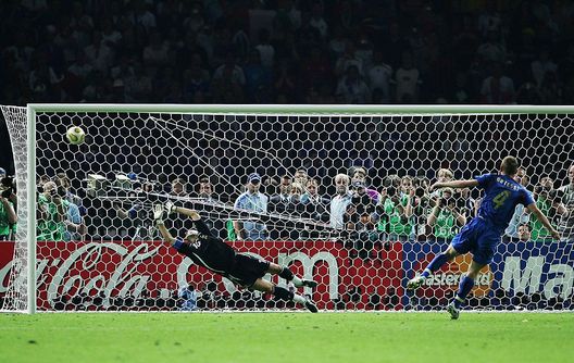 BERLIN - JULY 9: Daniele De Rossi of Italy scores a penalty kick past the dive of Fabien Barthez of France in a penalty shootout at the end the FIFA World Cup Germany 2006 Final match between Italy and France at the Olympic Stadium on July 9, 2006 in Berlin, Germany. (Photo by Alex Livesey/Getty Images) BERLIN - JULY 9: Daniele De Rossi of Italy scores a penalty kick past the dive of Fabien Barthez of France in a penalty shootout at the end the FIFA World Cup Germany 2006 Final match between Italy and France at the Olympic Stadium on July 9, 2006 in Berlin, Germany. (Photo by Alex Livesey/Getty Images)