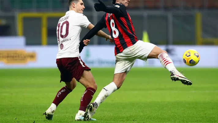 MILAN, ITALY - JANUARY 12: Sandro Tonali of A.C. Milan is challenged by Amer Gojak of Torino F.C. during the Coppa Italia match between AC Milan and Torino FC at Stadio Giuseppe Meazza on January 12, 2021 in Milan, Italy. Sporting stadiums around Italy remain under strict restrictions due to the Coronavirus Pandemic as Government social distancing laws prohibit fans inside venues resulting in games being played behind closed doors. (Photo by Marco Luzzani/Getty Images)
