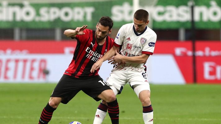 MILAN, ITALY - MAY 16: Hakan Calhanoglu of AC Milan holds off Razvan Marin of Cagliari Calcio during the Serie A match between AC Milan and Cagliari Calcio at Stadio Giuseppe Meazza on May 16, 2021 in Milan, Italy. Sporting stadiums around Italy remain under strict restrictions due to the Coronavirus Pandemic as Government social distancing laws prohibit fans inside venues resulting in games being played behind closed doors. (Photo by Marco Luzzani/Getty Images) MILAN, ITALY - MAY 16: Hakan Calhanoglu of AC Milan holds off Razvan Marin of Cagliari Calcio during the Serie A match between AC Milan and Cagliari Calcio at Stadio Giuseppe Meazza on May 16, 2021 in Milan, Italy. Sporting stadiums around Italy remain under strict restrictions due to the Coronavirus Pandemic as Government social distancing laws prohibit fans inside venues resulting in games being played behind closed doors. (Photo by Marco Luzzani/Getty Images)