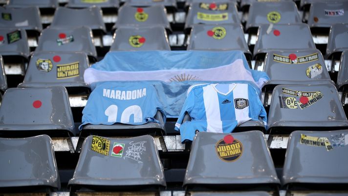 DORTMUND, GERMANY - NOVEMBER 28: An Argentina flag and shirts are laid out in the stands in memory of Diego Maradona prior to the Bundesliga match between Borussia Dortmund and 1. FC Koeln at Signal Iduna Park on November 28, 2020 in Dortmund, Germany. Football Stadiums around Europe remain empty due to the Coronavirus Pandemic as Government social distancing laws prohibit fans inside venues resulting in fixtures being played behind closed doors. (Photo by Friedemann Vogel - Pool/Getty Images) Argentina, calciatore ventenne si toglie la vita dopo esser stato svincolato dal club - immagine 1