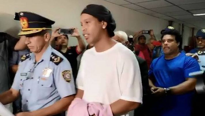 Ronaldinho e suo fratello arrivano ammanettati per testimoniare al processo in Paraguay Foto: Riproduzione / ABC Color Ronaldinho e suo fratello arrivano ammanettati per testimoniare al processo in Paraguay Foto: Riproduzione / ABC Color