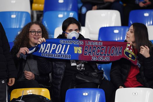 NAPLES, ITALY - FEBRUARY 25: SSC Napoli supporters, one of them with a mask due to Coronavirus, show a scarf before the UEFA Champions League round of 16 first leg match between SSC Napoli and FC Barcelona at Stadio San Paolo on February 25, 2020 in Naples, Italy. (Photo by Francesco Pecoraro/Getty Images) NAPLES, ITALY - FEBRUARY 25: SSC Napoli supporters, one of them with a mask due to Coronavirus, show a scarf before the UEFA Champions League round of 16 first leg match between SSC Napoli and FC Barcelona at Stadio San Paolo on February 25, 2020 in Naples, Italy. (Photo by Francesco Pecoraro/Getty Images)