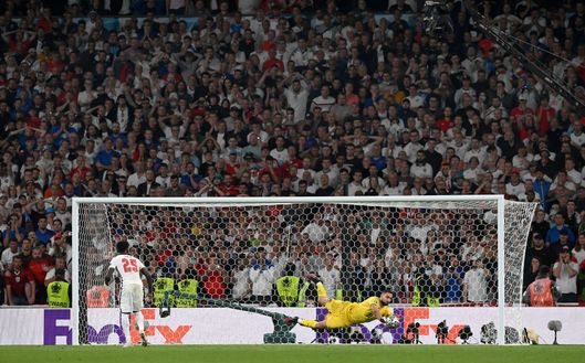 LONDON, ENGLAND - JULY 11: Bukayo Saka of England misses his team's sixth penalty in a penalty shoot out which is saved by Gianluigi Donnarumma of Italy during the penalty shoot out in the UEFA Euro 2020 Championship Final between Italy and England at Wembley Stadium on July 11, 2021 in London, England. (Photo by Paul Ellis - Pool/Getty Images) LONDON, ENGLAND - JULY 11: Bukayo Saka of England misses his team's sixth penalty in a penalty shoot out which is saved by Gianluigi Donnarumma of Italy during the penalty shoot out in the UEFA Euro 2020 Championship Final between Italy and England at Wembley Stadium on July 11, 2021 in London, England. (Photo by Paul Ellis - Pool/Getty Images)