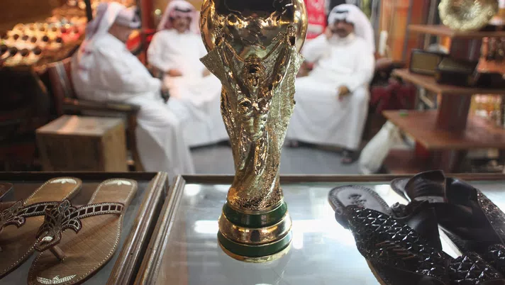 DOHA, QATAR - OCTOBER 24:  Arab men sit at a shoemaker's stall with a replica of the FIFA World Cup trophy in the Souq Waqif traditional market on October 24, 2011 in Doha, Qatar. Qatar will host the 2022 FIFA World Cup football competition and is slated to tackle a variety of infrastructure projects, including the construction of new stadiums.  (Photo by Sean Gallup/Getty Images)