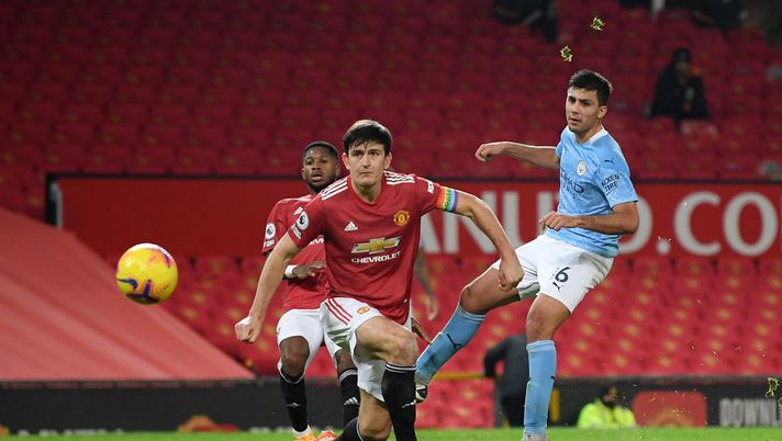 MANCHESTER, ENGLAND - DECEMBER 12: Rodrigo of Manchester City takes a shot as Harry Maguire of Manchester United looks on during the Premier League match between Manchester United and Manchester City at Old Trafford on December 12, 2020 in Manchester, England. The match will be played without fans, behind closed doors as a Covid-19 precaution. (Photo by Michael Regan/Getty Images) MANCHESTER, ENGLAND - DECEMBER 12: Rodrigo of Manchester City takes a shot as Harry Maguire of Manchester United looks on during the Premier League match between Manchester United and Manchester City at Old Trafford on December 12, 2020 in Manchester, England. The match will be played without fans, behind closed doors as a Covid-19 precaution. (Photo by Michael Regan/Getty Images)