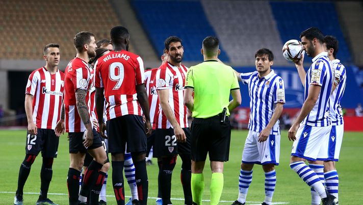 SEVILLE, SPAIN - APRIL 03: Rauel Garcia of Athletic Bilbao, David Silva of Real Sociedad and teammates from both teams surround Match Referee Xavier Estrada Fernandez during the Copa Del Rey Final match between Real Sociedad and Athletic Club at Estadio de La Cartuja on April 03, 2021 in Seville, Spain. Sporting stadiums around Spain remain under strict restrictions due to the Coronavirus Pandemic as Government social distancing laws prohibit fans inside venues resulting in games being played behind closed doors. (Photo by Fran Santiago/Getty Images) David Silva rientra per il derby basco e la Real Sociedad sorride - immagine 1