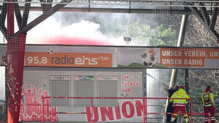 BERLIN, GERMANY - APRIL 04: Grounds staff attempt to distinguish pyrotechnics set off by fans outside the stadium during the Bundesliga match between 1. FC Union Berlin and Hertha BSC at Stadion An der Alten Foersterei on April 04, 2021 in Berlin, Germany. Sporting stadiums around Germany remain under strict restrictions due to the Coronavirus Pandemic as Government social distancing laws prohibit fans inside venues resulting in games being played behind closed doors. (Photo by Clemens Bilan - Pool/Getty Images) BERLIN, GERMANY - APRIL 04: Grounds staff attempt to distinguish pyrotechnics set off by fans outside the stadium during the Bundesliga match between 1. FC Union Berlin and Hertha BSC at Stadion An der Alten Foersterei on April 04, 2021 in Berlin, Germany. Sporting stadiums around Germany remain under strict restrictions due to the Coronavirus Pandemic as Government social distancing laws prohibit fans inside venues resulting in games being played behind closed doors. (Photo by Clemens Bilan - Pool/Getty Images)