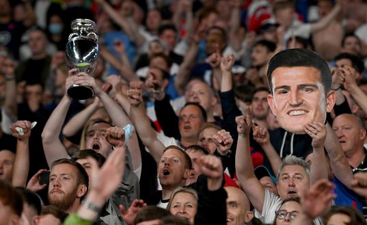 LONDON, ENGLAND - JULY 07: Fans of England with a replica Euro 2020 trophy and a face mask of Harry Maguire of England celebrate their side's victory after the UEFA Euro 2020 Championship Semi-final match between England and Denmark at Wembley Stadium on July 07, 2021 in London, England. (Photo by Paul Ellis - Pool/Getty Images) LONDON, ENGLAND - JULY 07: Fans of England with a replica Euro 2020 trophy and a face mask of Harry Maguire of England celebrate their side's victory after the UEFA Euro 2020 Championship Semi-final match between England and Denmark at Wembley Stadium on July 07, 2021 in London, England. (Photo by Paul Ellis - Pool/Getty Images)