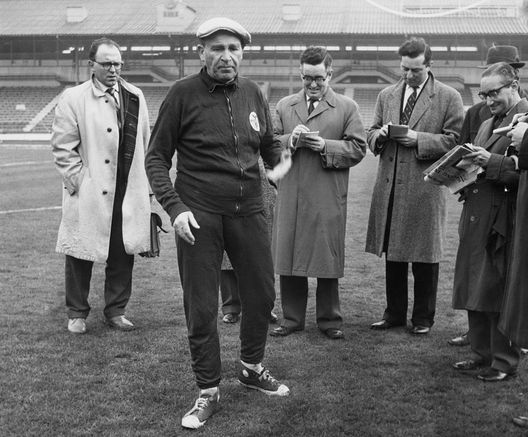 Benfica coach and manager Bela Guttmann (1900 - 1981) with a group of journalists at White City in London, 4th April 1962. He had just accused Tottenham Hotspur of watering the pitch at White Hart Lane, in preparation for their game against Benfica the next day. The match was the second leg semi-final of the European Cup. (Photo by Keystone/Hulton Archive/Getty Images) Benfica coach and manager Bela Guttmann (1900 - 1981) with a group of journalists at White City in London, 4th April 1962. He had just accused Tottenham Hotspur of watering the pitch at White Hart Lane, in preparation for their game against Benfica the next day. The match was the second leg semi-final of the European Cup. (Photo by Keystone/Hulton Archive/Getty Images)