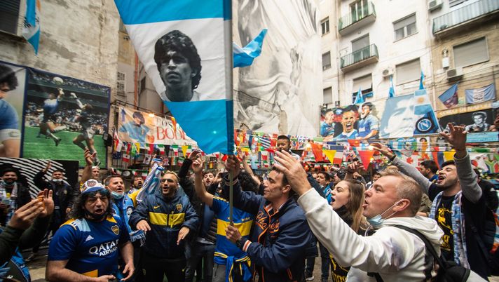 NAPLES, ITALY - NOVEMBER 25: Supporters of Boca Juniors and Napoli near the mural by Diego Armando Maradona in the Quartieri Spagnoli on November 25, 2021 in Naples, Italy. A year on after the football star's death, Maradona is still the idol of all Neapolitans, marked by tributes all over the city. (Photo by Ivan Romano/Getty Images) NAPLES, ITALY - NOVEMBER 25: Supporters of Boca Juniors and Napoli near the mural by Diego Armando Maradona in the Quartieri Spagnoli on November 25, 2021 in Naples, Italy. A year on after the football star's death, Maradona is still the idol of all Neapolitans, marked by tributes all over the city. (Photo by Ivan Romano/Getty Images)