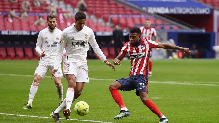 MADRID, SPAIN - MARCH 07: Raphael Varane of Real Madrid clears the ball whilst under pressure from Thomas Lemar of Atletico de Madrid during the La Liga Santander match between Atletico de Madrid and Real Madrid at Estadio Wanda Metropolitano on March 07, 2021 in Madrid, Spain. Sporting stadiums around Spain remain under strict restrictions due to the Coronavirus Pandemic as Government social distancing laws prohibit fans inside venues resulting in games being played behind closed doors. (Photo by Denis Doyle/Getty Images) MADRID, SPAIN - MARCH 07: Raphael Varane of Real Madrid clears the ball whilst under pressure from Thomas Lemar of Atletico de Madrid during the La Liga Santander match between Atletico de Madrid and Real Madrid at Estadio Wanda Metropolitano on March 07, 2021 in Madrid, Spain. Sporting stadiums around Spain remain under strict restrictions due to the Coronavirus Pandemic as Government social distancing laws prohibit fans inside venues resulting in games being played behind closed doors. (Photo by Denis Doyle/Getty Images)